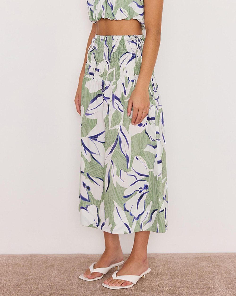 Person wearing a green and white floral dress on a plain background