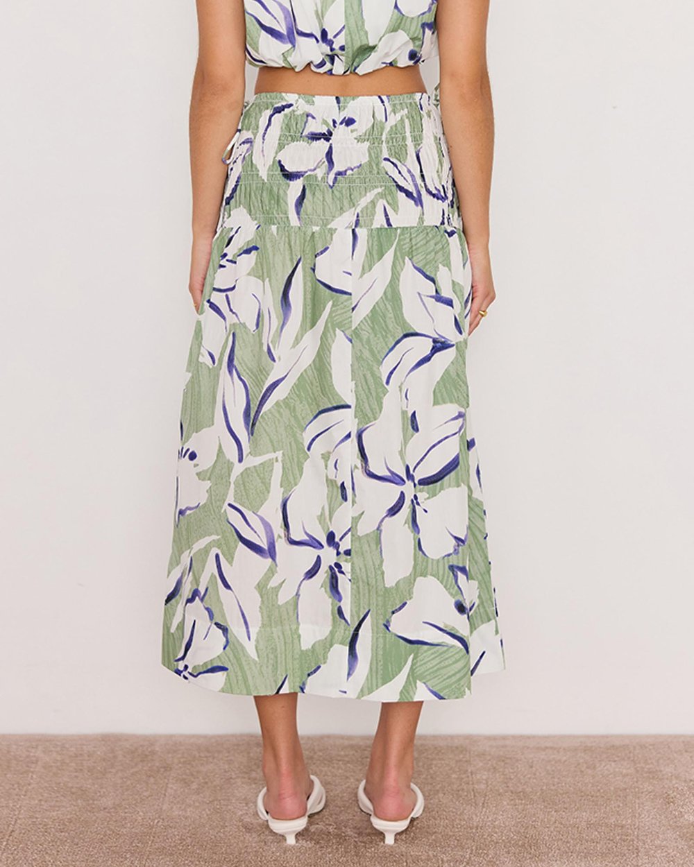 Person wearing a green floral skirt with a white background