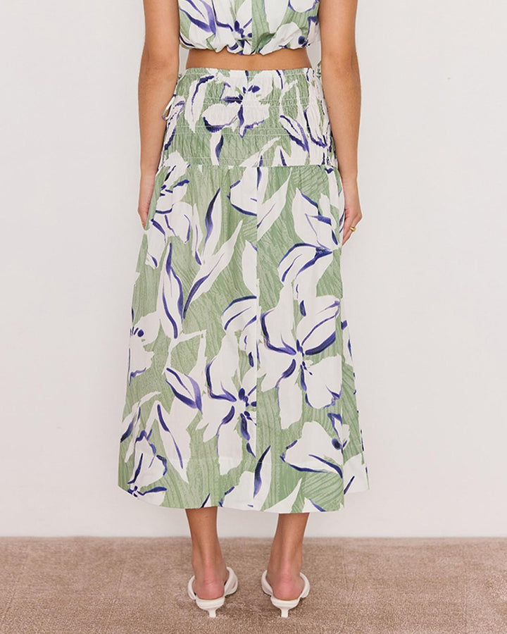 Person wearing a green floral skirt with a white background