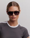 Woman wearing dark sunglasses against a plain background