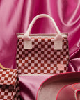 Checkered bag with white handles on a pink fabric background