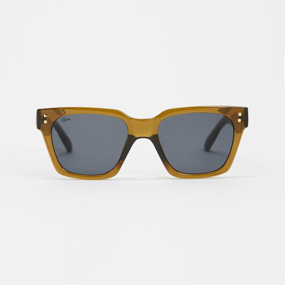 A pair of square sunglasses with a translucent amber-brown acetate frame and dark gray lenses, shown against a plain light gray background.