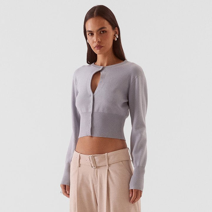 A woman modeling a light lavender long-sleeve crop top with a keyhole cutout and beige wide-leg trousers, standing against a light gray studio background.