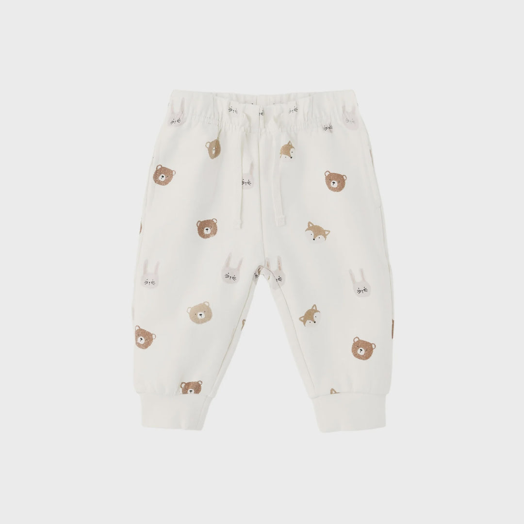 A pair of baby jogger pants in off-white, featuring an all-over print of cute brown teddy bears, foxes, and rabbits. The pants have an elastic waistband with a white drawstring and ribbed ankle cuffs, shown against a light gray background.