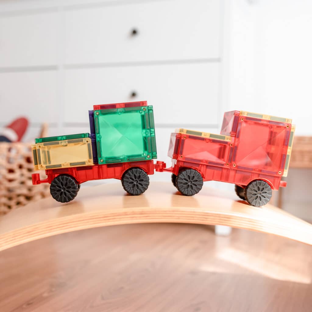Connetix Colorful toy train cars on a wooden track with a white background