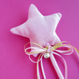 Star-shaped white pillow with a pink ribbon on a pink background