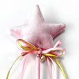 Pink star-shaped pillow with a gold bell and ribbons on a white background