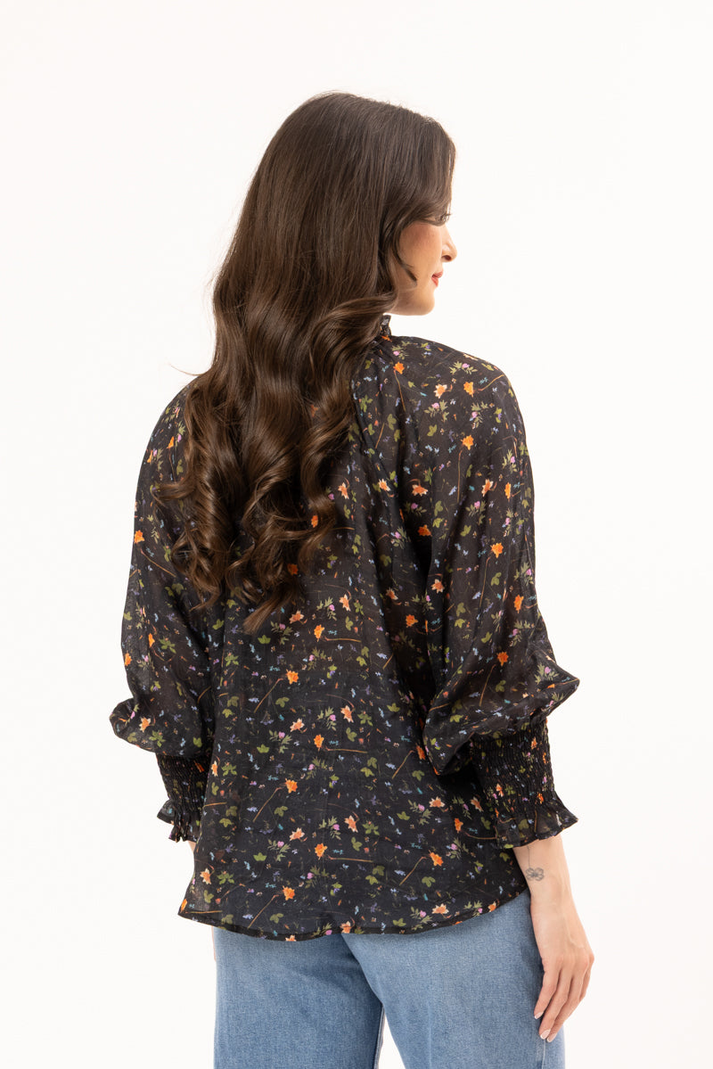 Woman wearing a black floral blouse with long sleeves on a white background