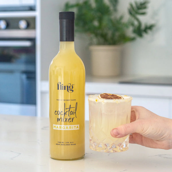 Bottle of fling cocktail mixer Margarita with a glass of margarita in a kitchen setting