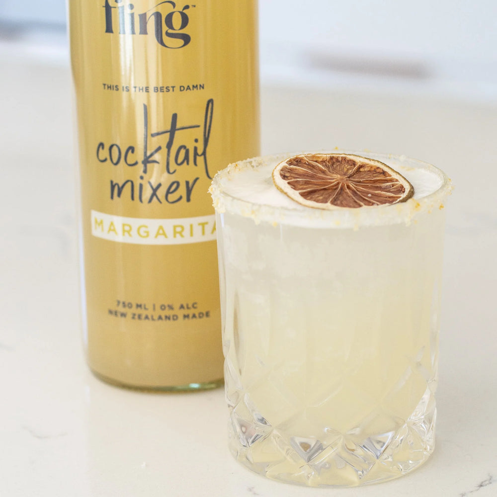 Bottle of Fling cocktail mixer with a glass of margarita on a white background
