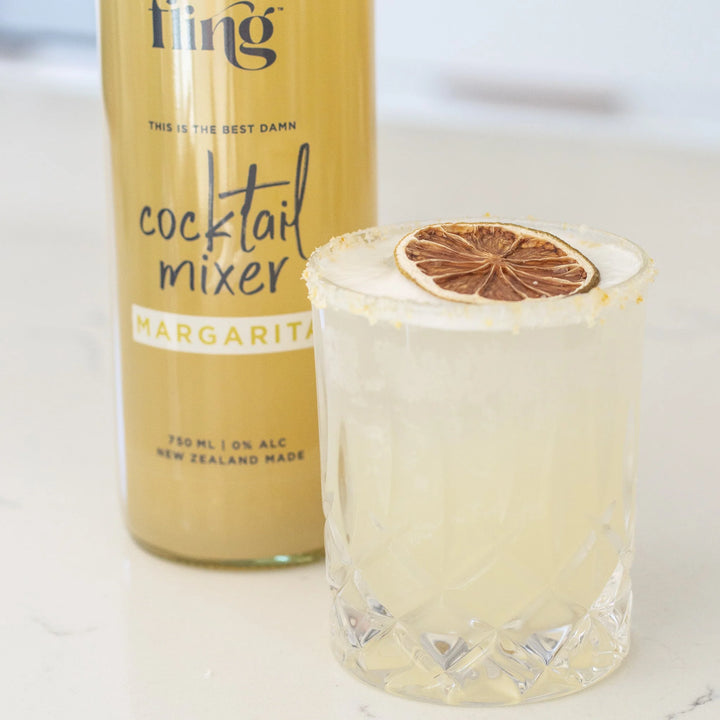 Bottle of Fling cocktail mixer with a glass of margarita on a white background