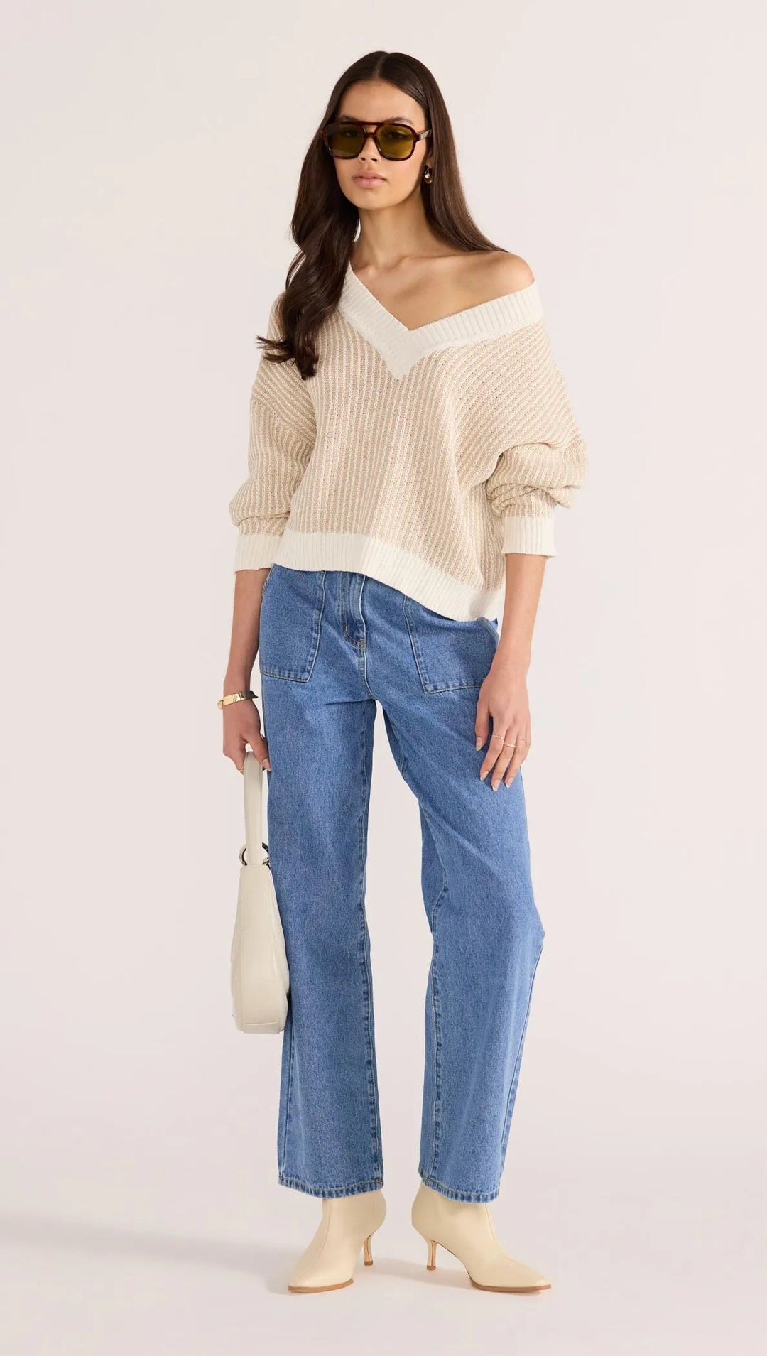 Woman wearing a beige off-shoulder minkpink sweater, available from The Collective