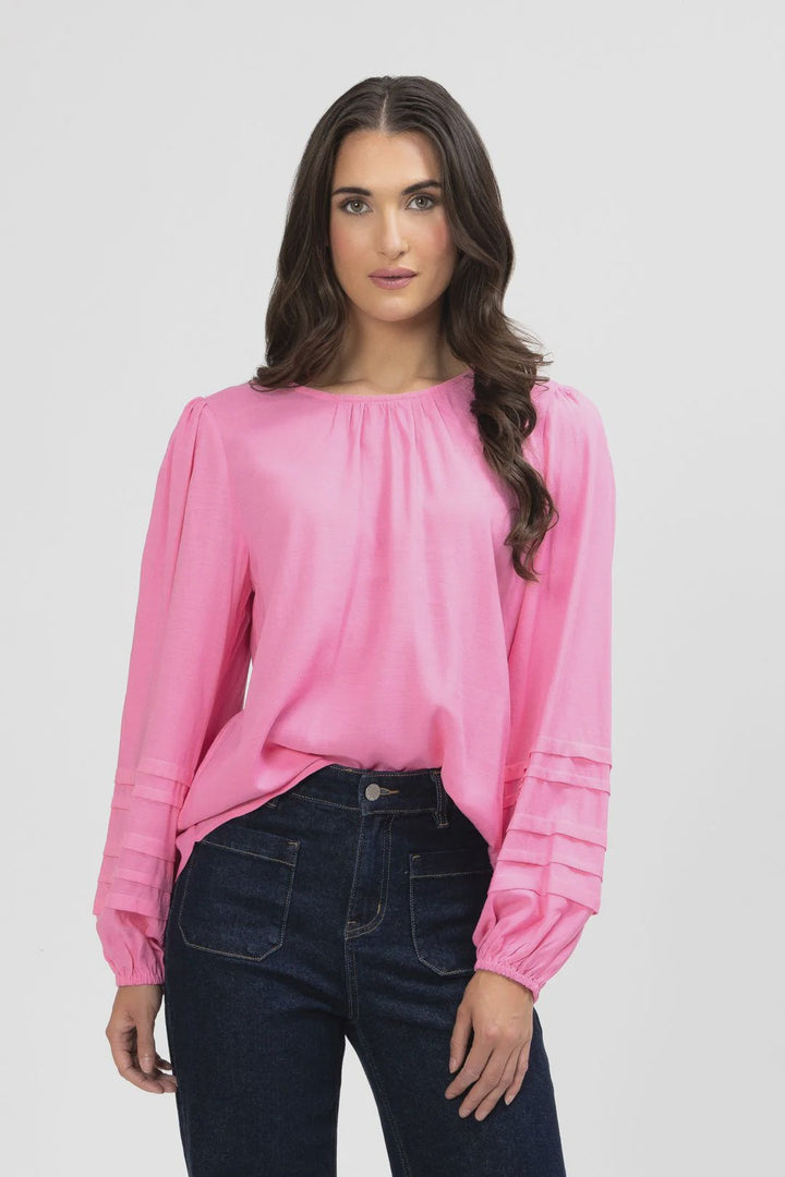 Woman wearing a pink blouse and dark jeans on a white background