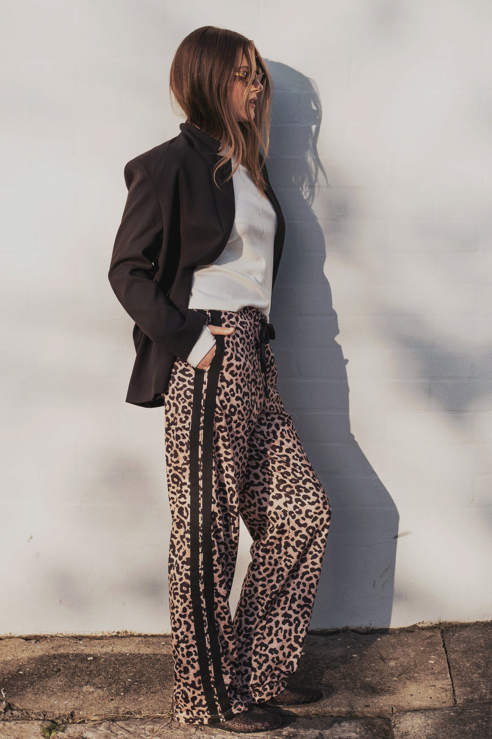 Person wearing a black blazer, white shirt, and cartel & willow leopard print pants against a light background
