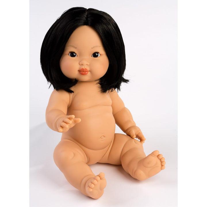 A realistic plastic baby doll with black hair, sitting on a plain white studio background.