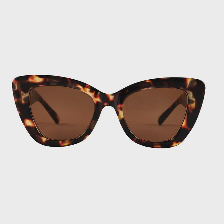 Cat-eye sunglasses with a brown and black tortoiseshell patterned frame and brown lenses, shown against a light gray background.