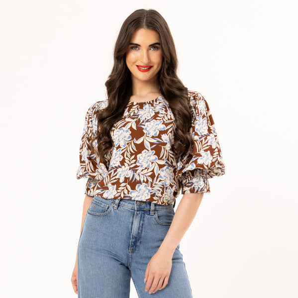 Woman wearing a floral blouse and blue jeans on a white background