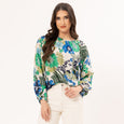 Woman wearing a colorful floral blouse and white pants on a white background