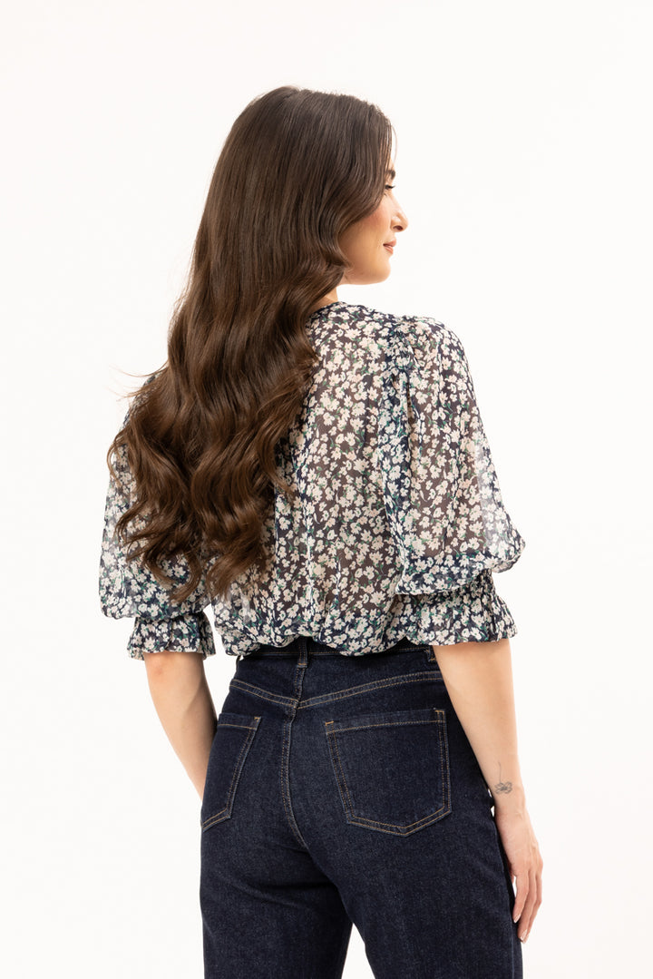 Woman wearing a floral blouse and dark jeans on a white background