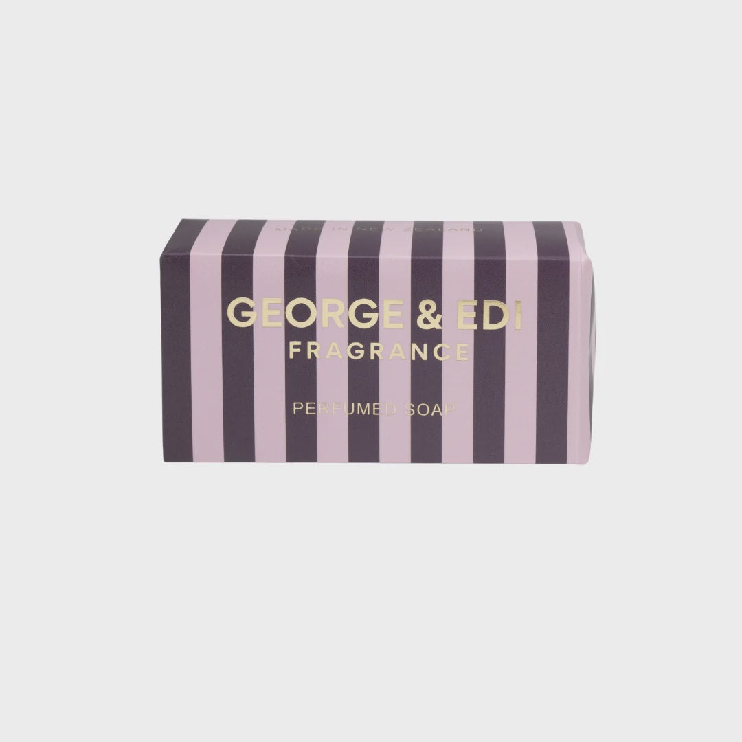 A rectangular product box for George & Edi Fragrance Perfume Soap, featuring vertical stripes in lavender pink and dark purple with gold lettering, set against a solid light gray background.