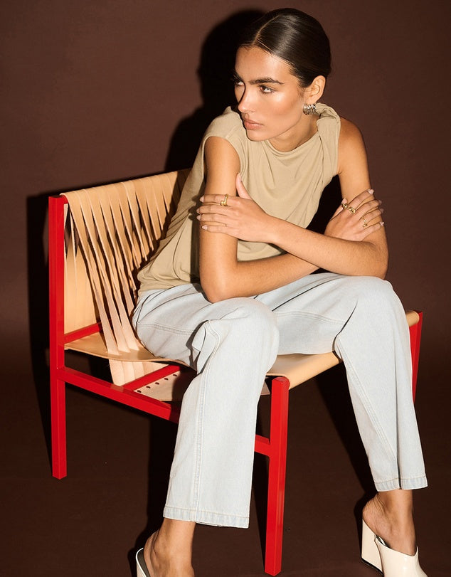 Woman sitting on a red chair with a beige backrest against a brown background
