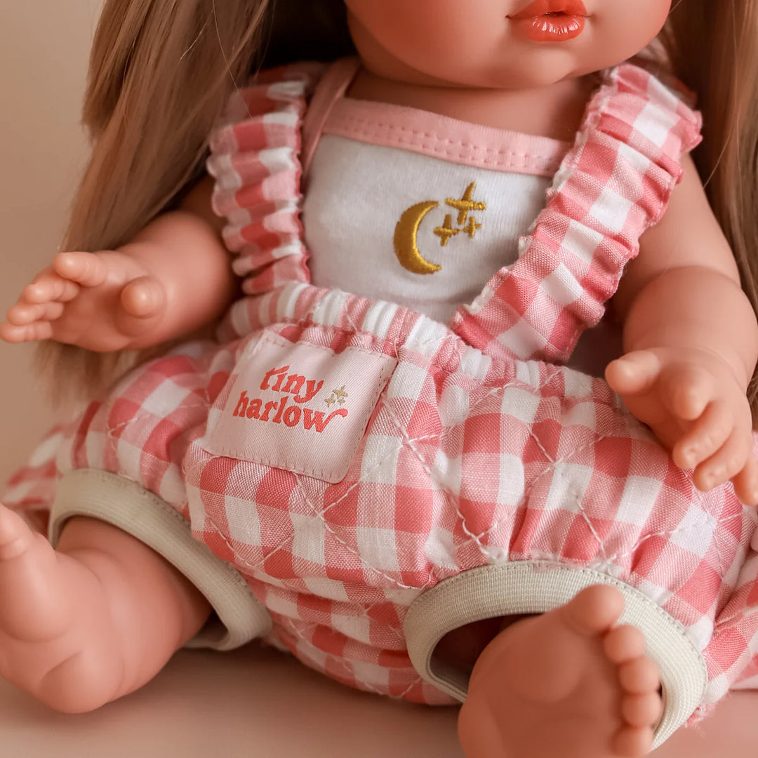 Doll wearing a red and white checkered outfit with 'tiny harlow' branding.