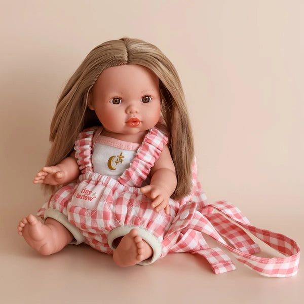 Doll wearing a pink checkered outfit with a matching dress on a beige background