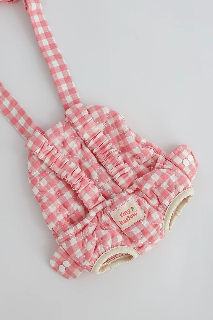 Pink checkered baby romper with a matching headband on a light gray background