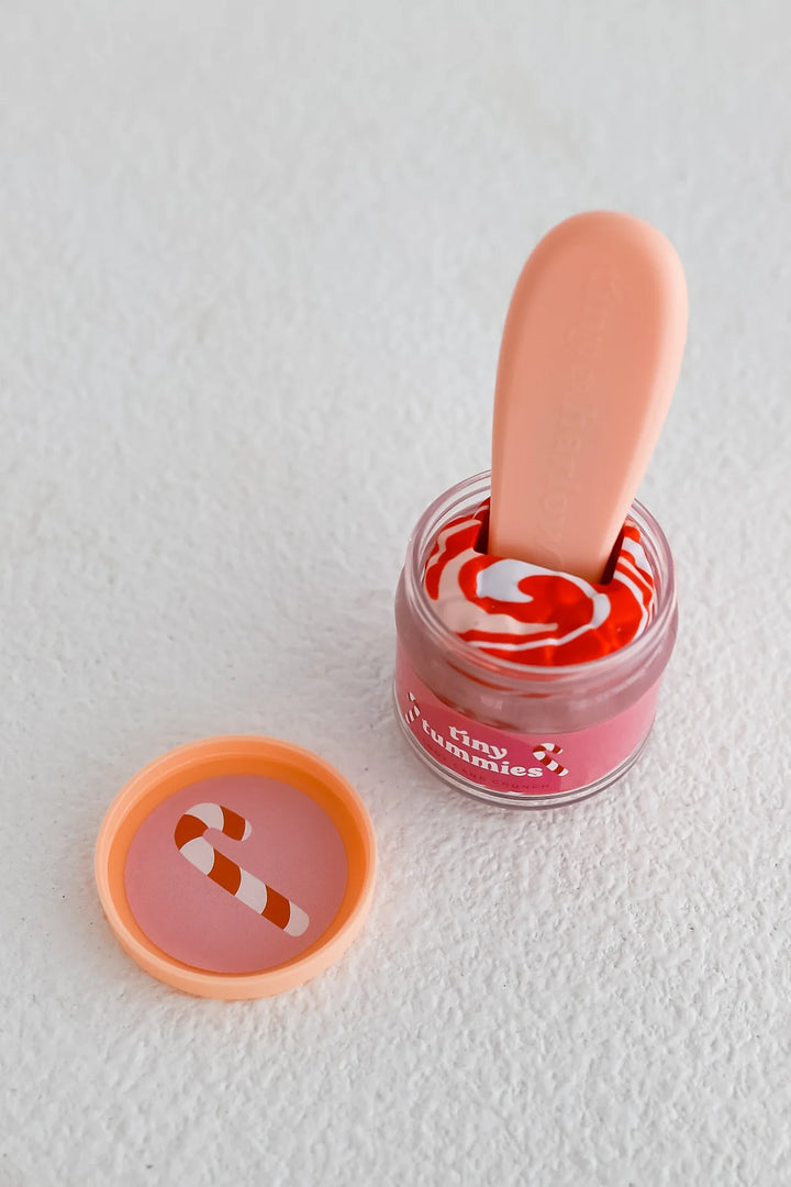 Small jar of pink lip balm with a applicator on a white background