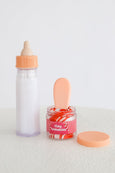 Baby bottle, jar with spoon, and container labeled 'tiny tummies' on a white background