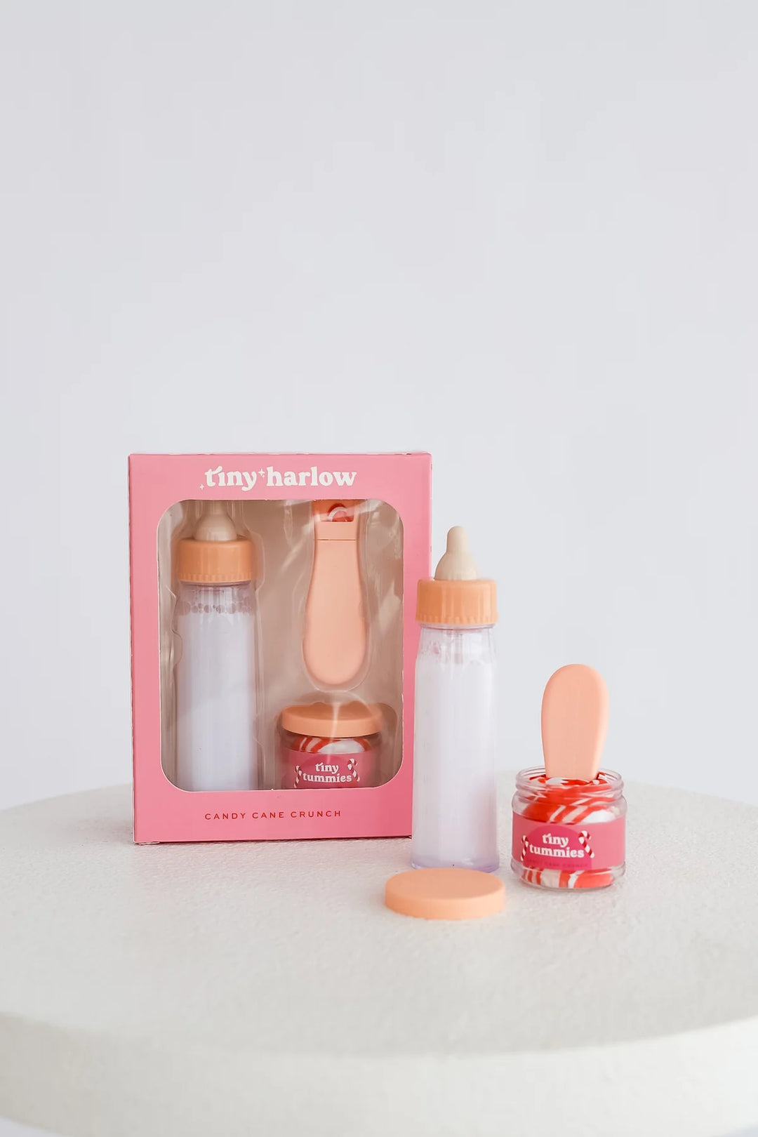 Baby product set with bottles and jar on a white surface, featuring 'tiny harlow' branding.