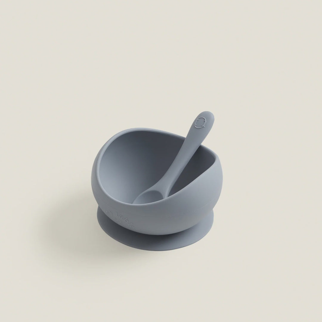 Blue baby bowl with spoon on a light beige background