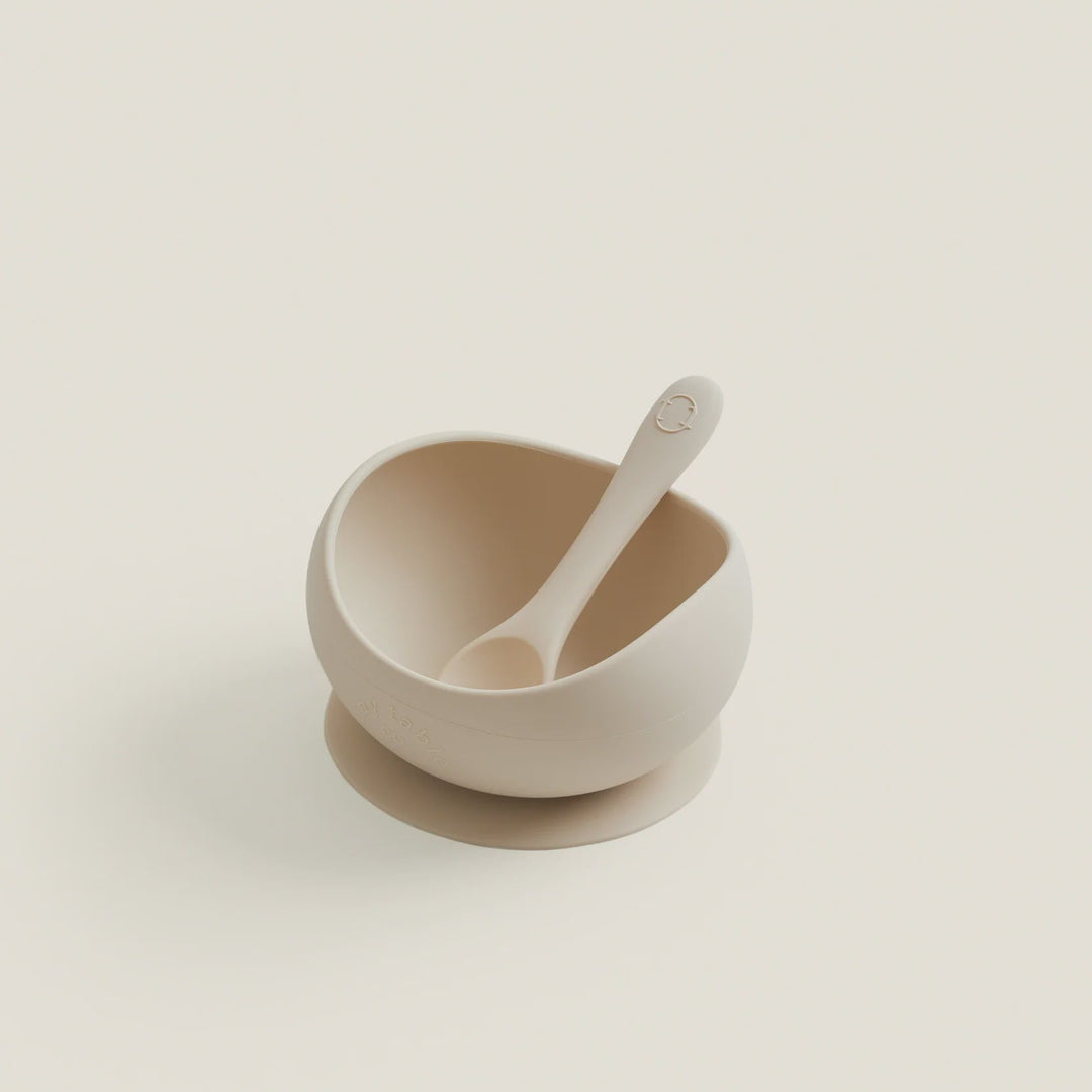 Beige ceramic bowl with a spoon on a light beige background