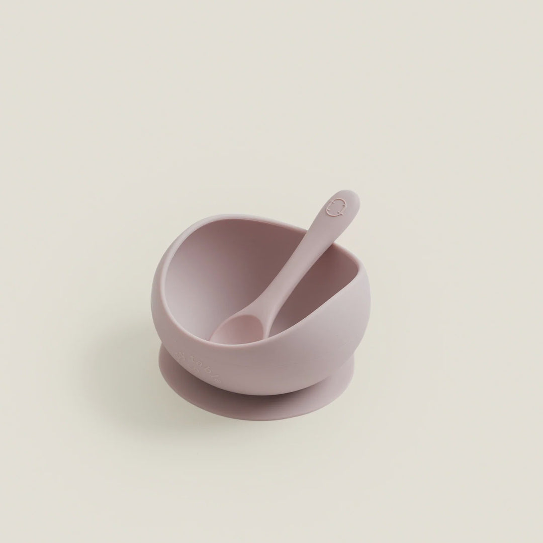Pink bowl with a matching spoon on a light beige background