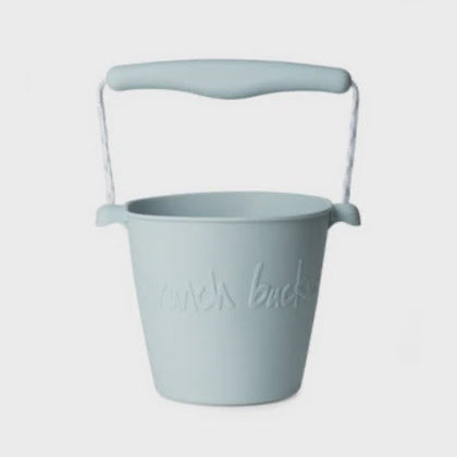 A light blue plastic bucket with a matching handle and rope loop, featuring the embossed text 'munch bucks' on the front, set against a plain light gray background.