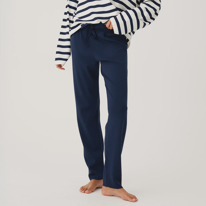 Woman wearing a navy and white striped sweater and blue pants on a white background
