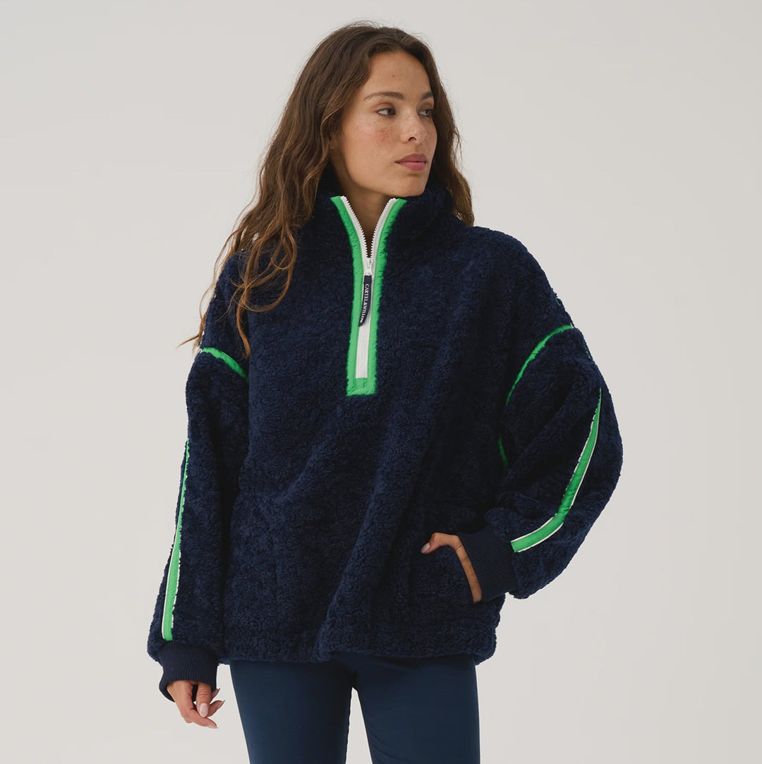 Woman wearing a navy fleece pullover with green accents on a white background