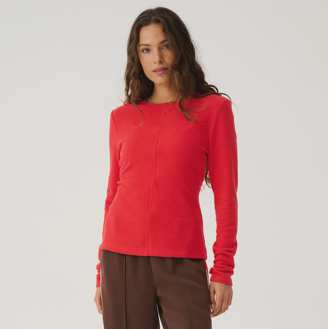 Woman wearing a red top and brown pants on a white background
