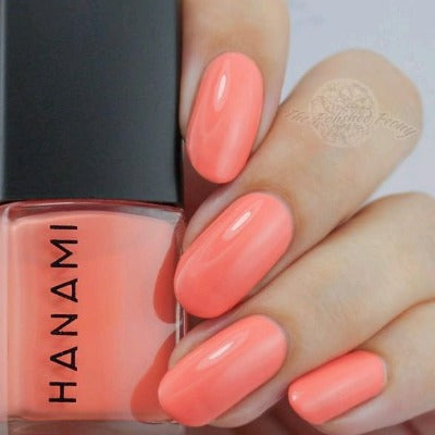 Hand with coral nail polish holding a bottle of HANAMI nail polish.