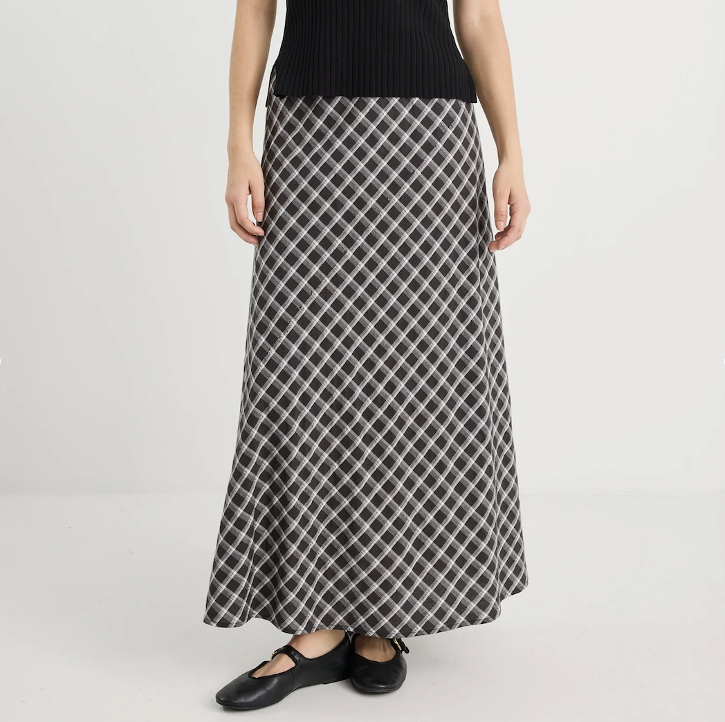 Person wearing a long, patterned skirt on a plain background