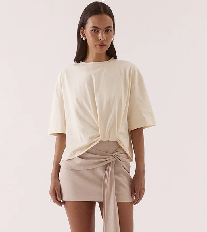 Woman wearing a cream top and beige skirt on a white background