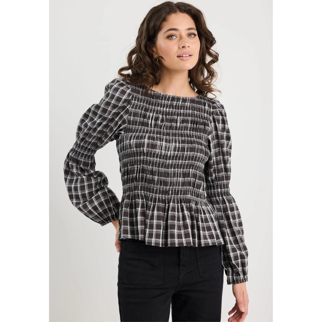 Woman wearing a black and white checkered blouse with a plain background