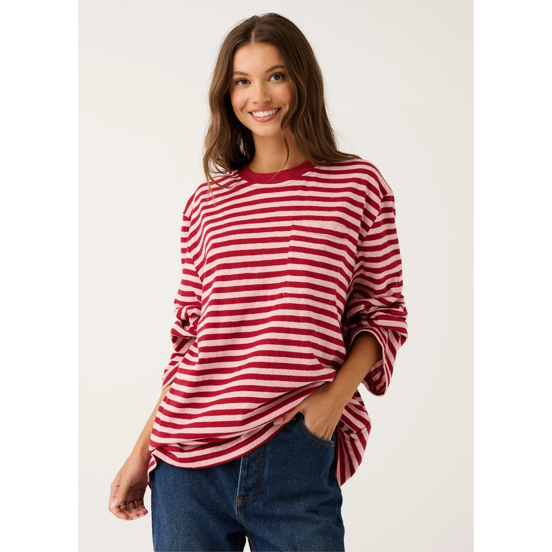A woman modeling a red and white horizontally striped long-sleeve top with a crew neck, paired with blue jeans, against a plain light background.