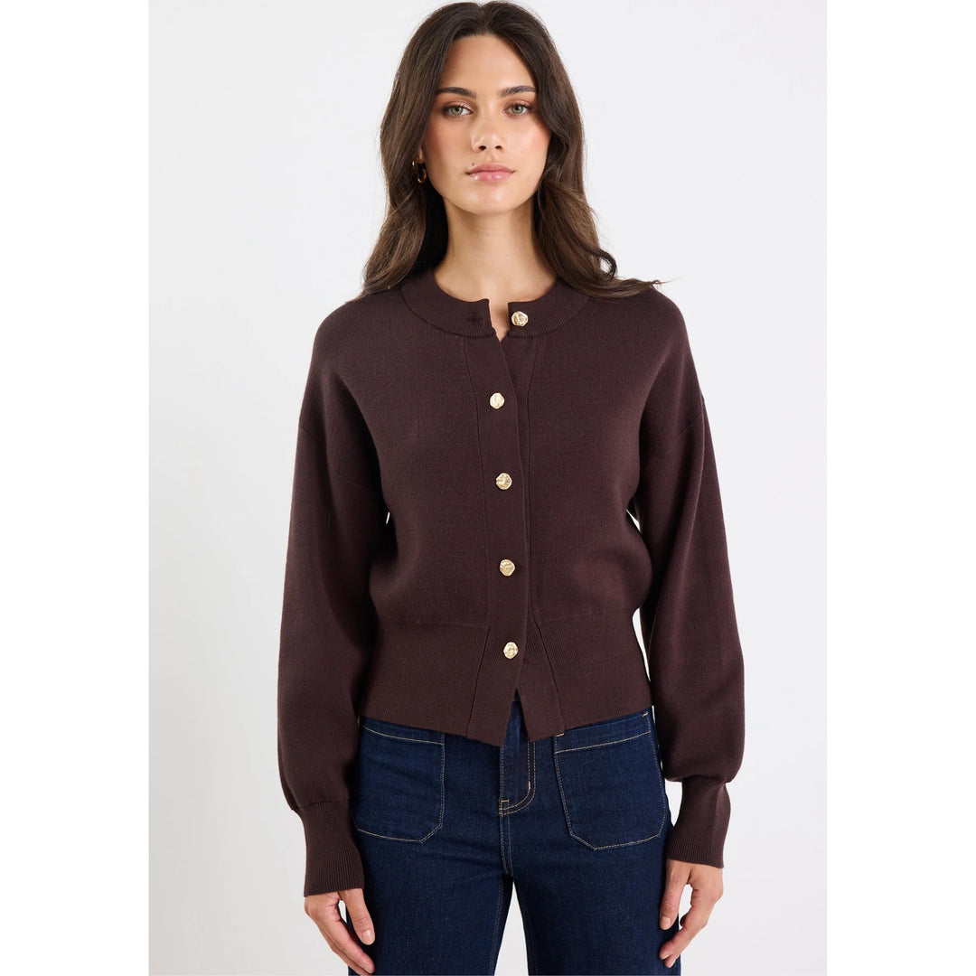 Woman wearing a brown cardigan with gold buttons on a white background