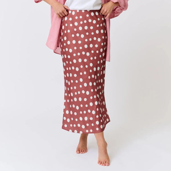 Woman wearing a pink polka dot skirt and white shirt on a white background