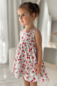 Young girl wearing a floral milky dress with cherries indoors.
