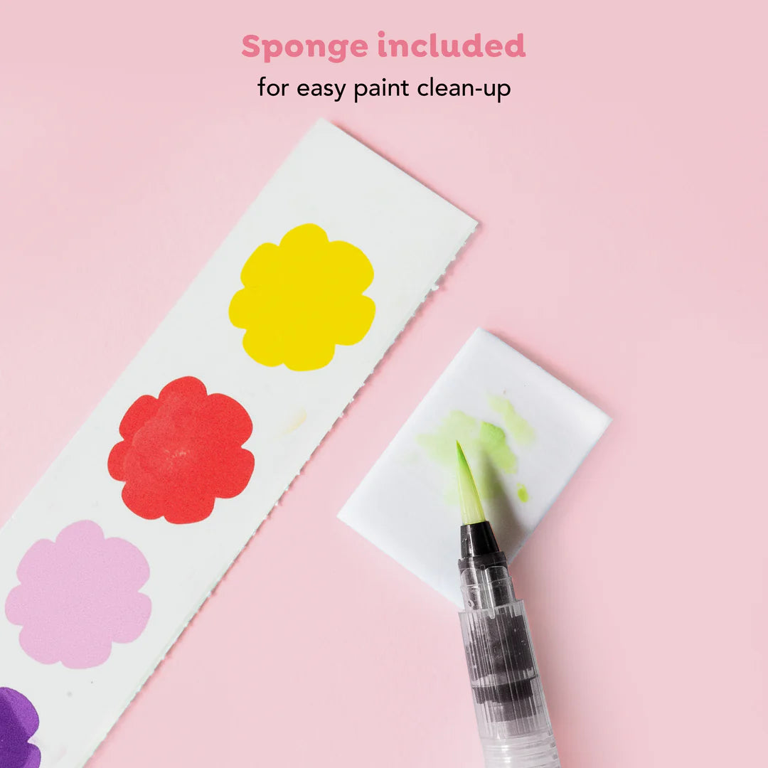 Colorful flower designs on paper with a paintbrush and sponge on a pink background