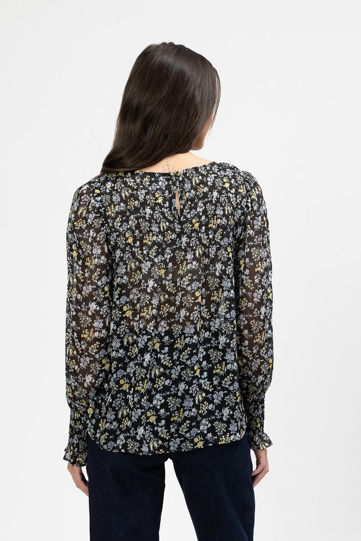 Woman wearing a floral hug me blouse with a plain background