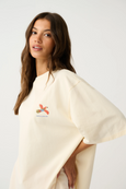 Woman wearing a cream-colored poncho with a logo on a white background
