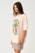 Woman wearing a pink oversized t-shirt with a palm tree graphic and leopard print shorts on a white background